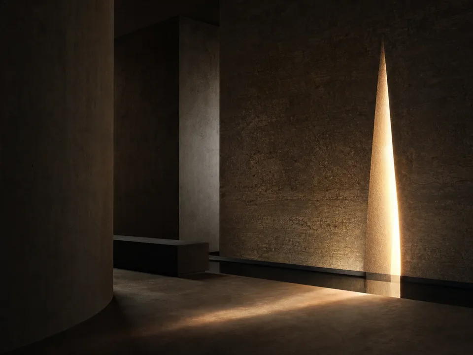 Faisceau de lumière traversant une paroi minérale dans un espace mémoriel contemporain.