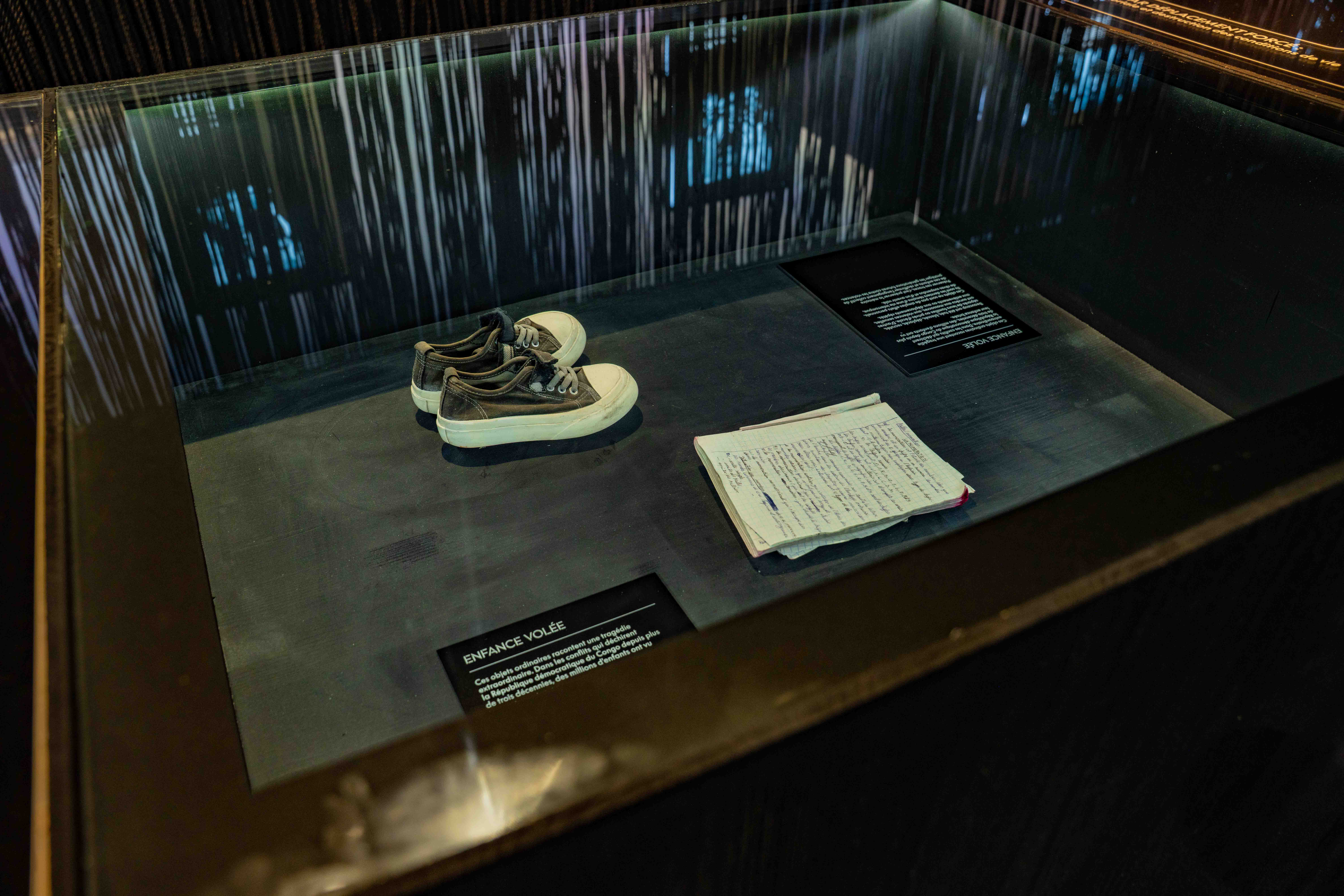 Vitrine présentant une paire de chaussures et un document manuscrit