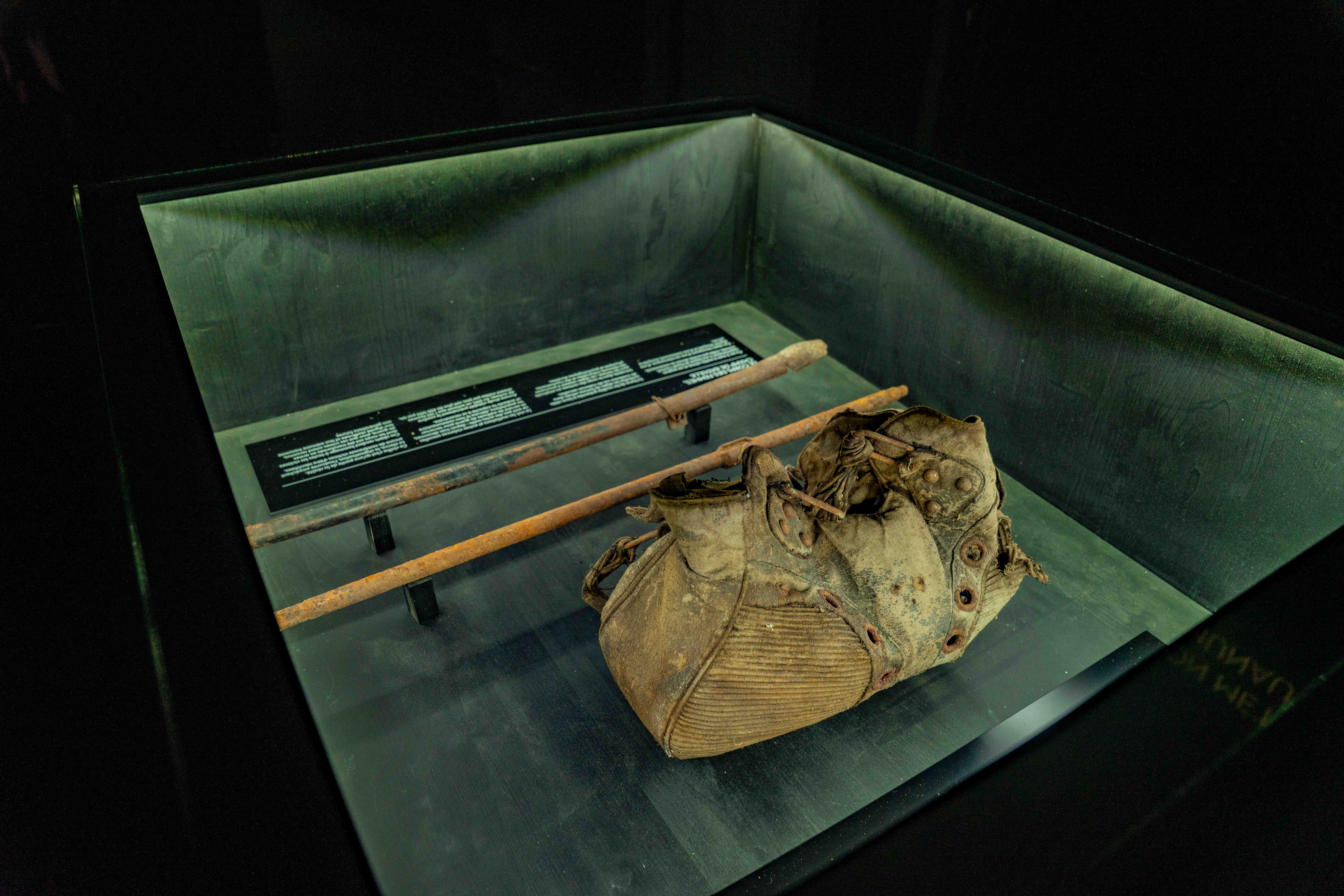 Vitrine présentant une chaussure usée et des barres métalliques