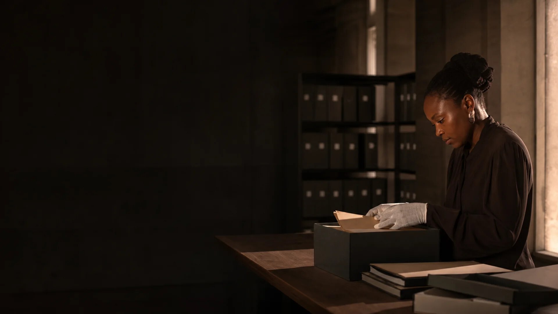 Archiviste consultant des documents dans une salle de lecture contemporaine.